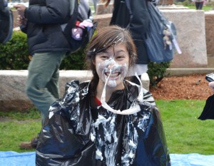 A student covered in whipped cream after taking a pie to the face at COMSA's pie-ing station | Photo by Alene Bouranova