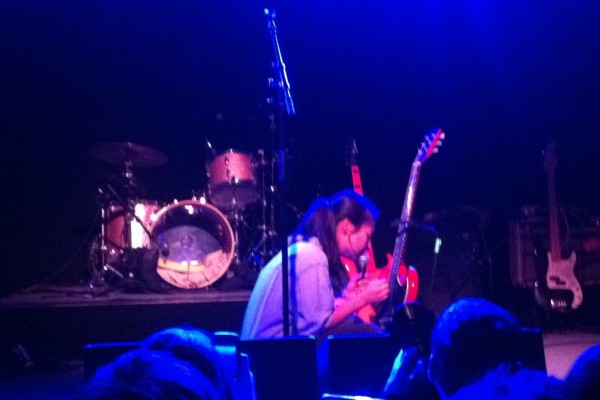 Mitski unorthodoxly strumming her guitar in its stand while wrenching hearts during "Class of 2013."